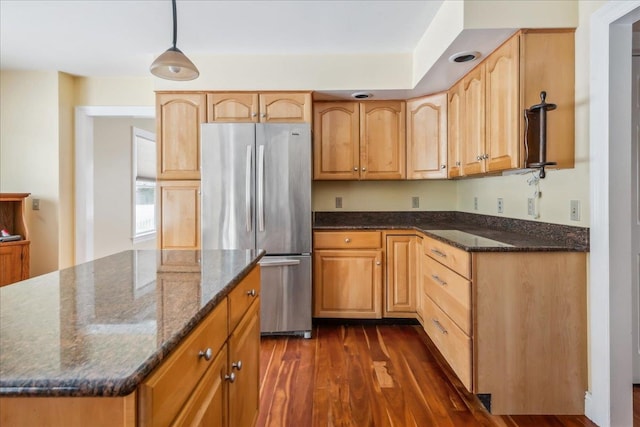 kitchen with dark wood-style flooring, dark stone countertops, a kitchen island, and freestanding refrigerator