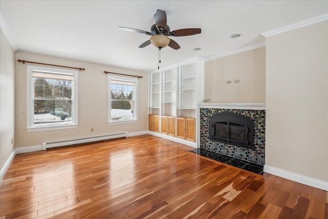 unfurnished living room with a baseboard heating unit, wood finished floors, baseboards, ornamental molding, and a tiled fireplace