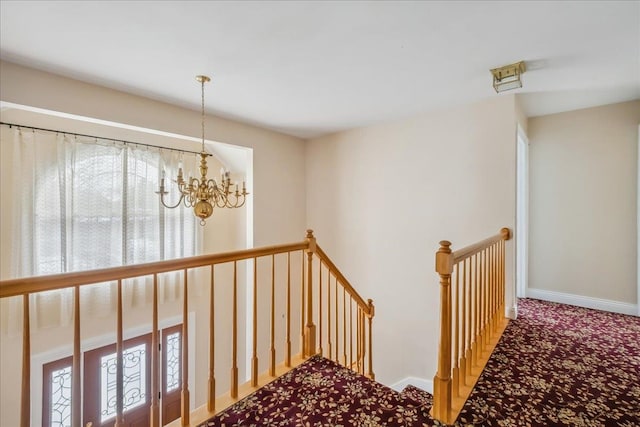 stairway with baseboards, a chandelier, and carpet flooring