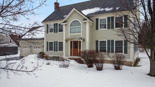 colonial-style house featuring a garage and a chimney