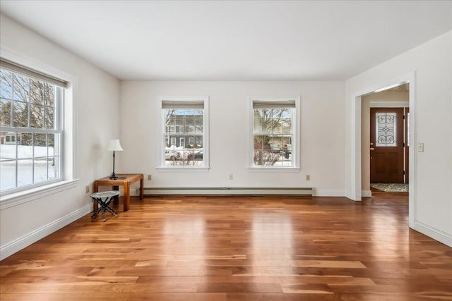 interior space featuring a wealth of natural light, baseboards, a baseboard heating unit, and wood finished floors