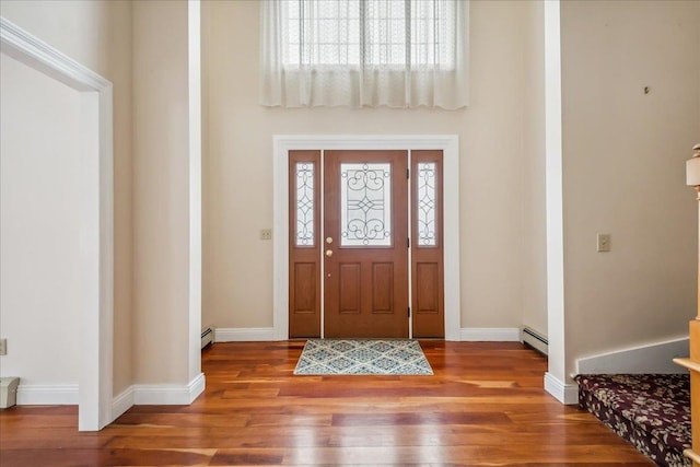 entrance foyer featuring a baseboard heating unit, baseboards, and wood finished floors