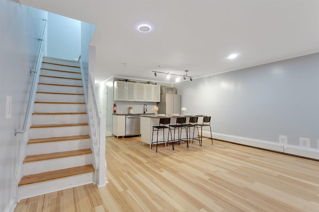 kitchen with dishwasher, a breakfast bar, freestanding refrigerator, white cabinetry, and a sink