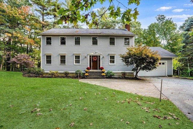 colonial home with an attached garage, driveway, a chimney, and a front yard