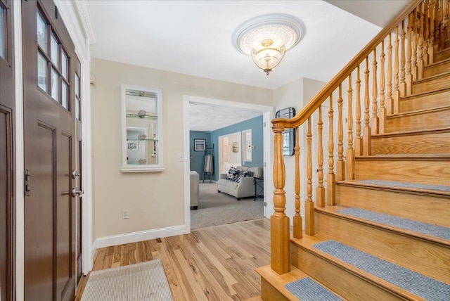 foyer featuring baseboards, stairway, and wood finished floors