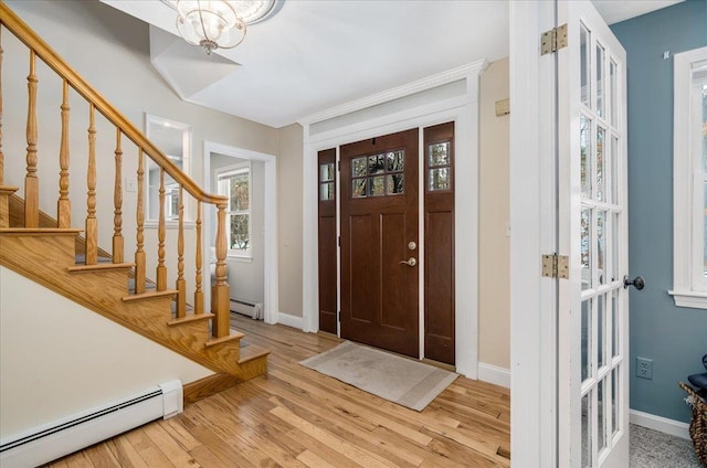 foyer with stairs, baseboards, baseboard heating, and wood finished floors