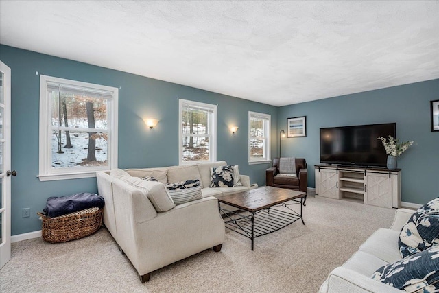 carpeted living room featuring a textured ceiling, a wealth of natural light, and baseboards