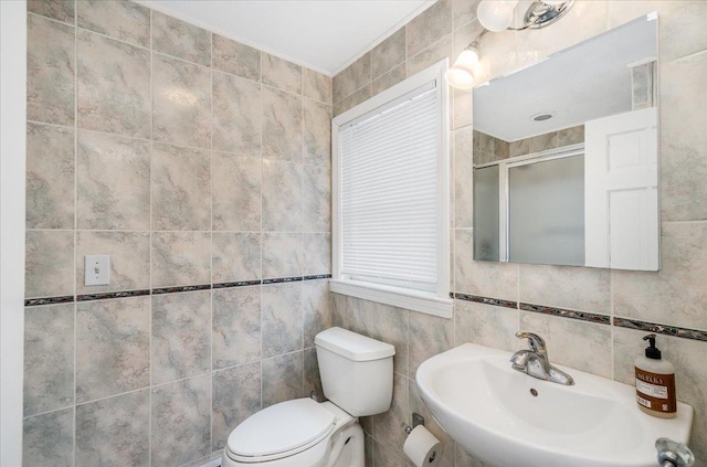 full bath featuring toilet, a shower stall, tile walls, and a sink