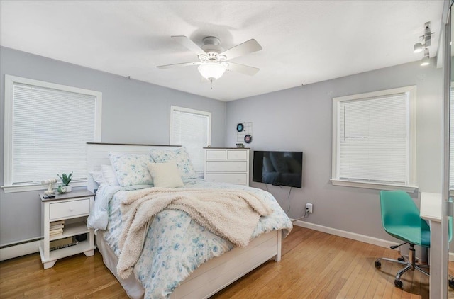 bedroom with ceiling fan, wood finished floors, and baseboards