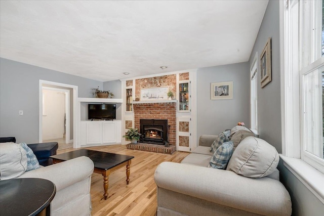 living room with a brick fireplace and light wood-style floors