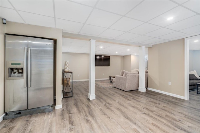 interior space featuring a drop ceiling, baseboards, and wood finished floors