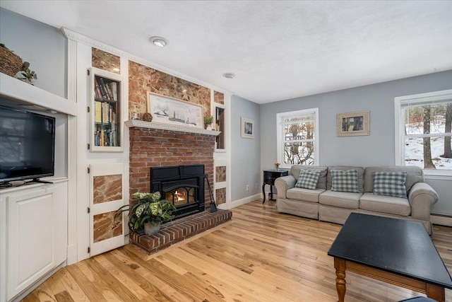 living area featuring light wood finished floors, a fireplace, and a healthy amount of sunlight