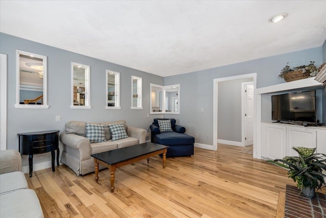 living area featuring baseboards and light wood finished floors