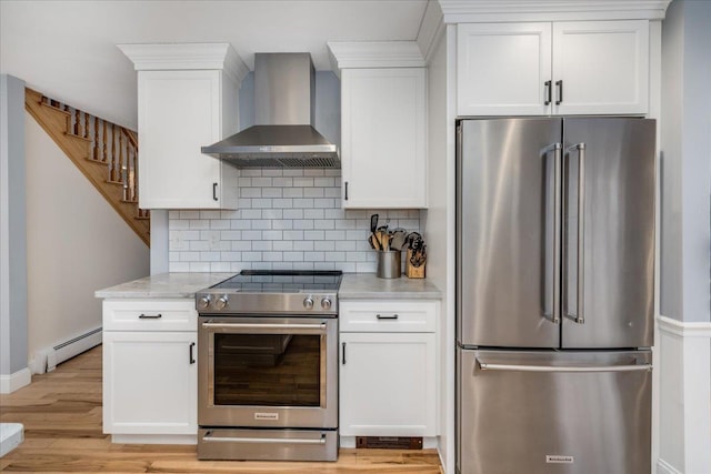 kitchen with wall chimney exhaust hood, baseboard heating, white cabinetry, and stainless steel appliances