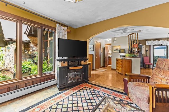 living area with a baseboard heating unit, arched walkways, and ceiling fan