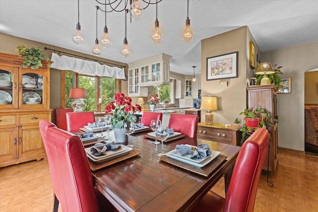 dining area with a textured ceiling and light wood finished floors