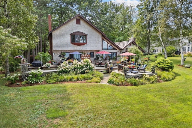 back of house with a standing seam roof, a patio, a chimney, and a lawn