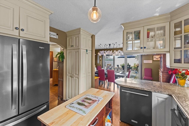 kitchen with glass insert cabinets, freestanding refrigerator, arched walkways, and cream cabinets