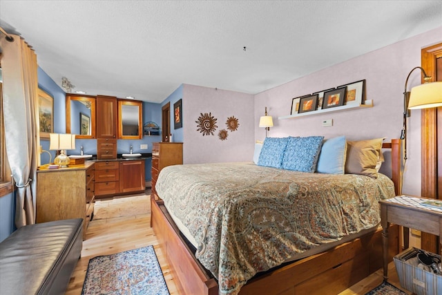 bedroom with light wood-style floors and a textured ceiling