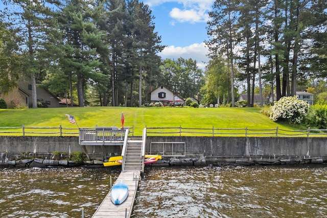 dock area with a water view, fence, and a yard