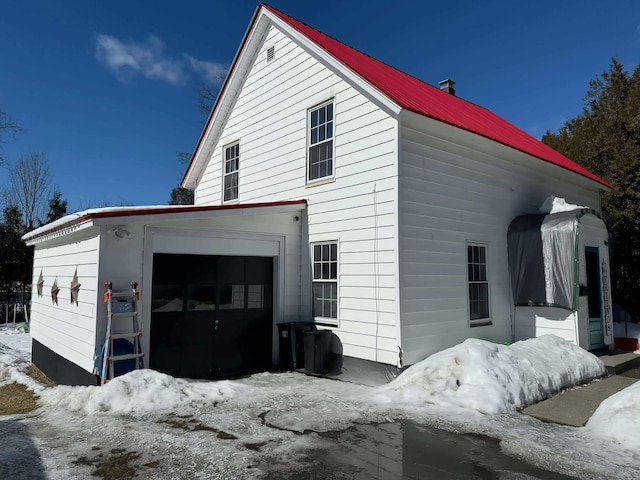 view of snow covered exterior with a garage and metal roof