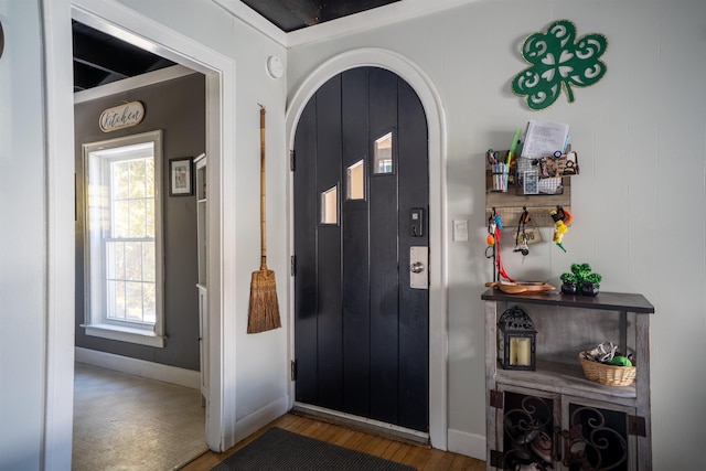 entrance foyer featuring arched walkways, wood finished floors, and baseboards