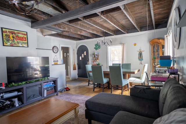 living area with arched walkways, beamed ceiling, and wood finished floors