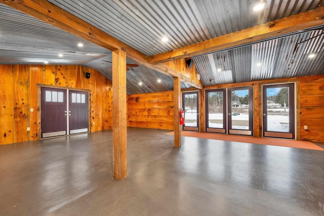 interior space featuring lofted ceiling with beams, recessed lighting, finished concrete floors, and wooden walls