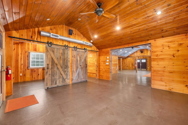 additional living space featuring lofted ceiling, a barn door, wooden walls, and a ceiling fan