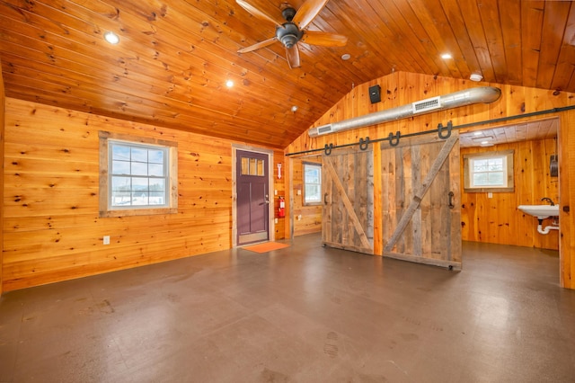 interior space featuring a barn door, visible vents, lofted ceiling, wooden ceiling, and wood walls