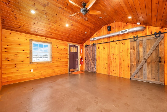 interior space featuring a barn door, wooden walls, lofted ceiling, wood ceiling, and ceiling fan