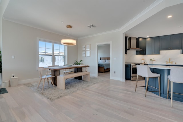 dining area with crown molding, light wood-style flooring, and baseboards