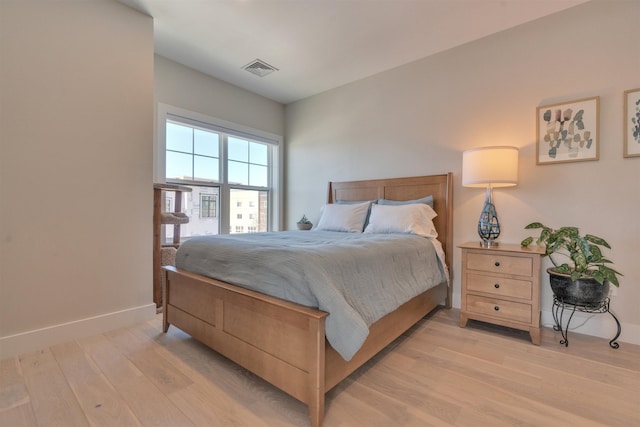 bedroom featuring light wood-style flooring, visible vents, and baseboards