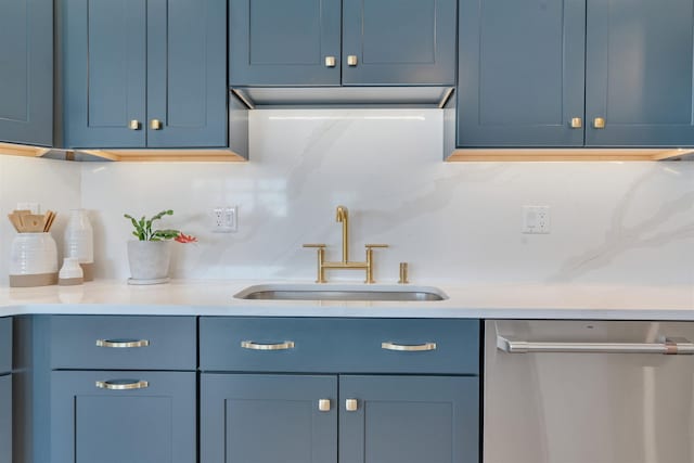 kitchen with tasteful backsplash, light countertops, stainless steel dishwasher, a sink, and blue cabinets