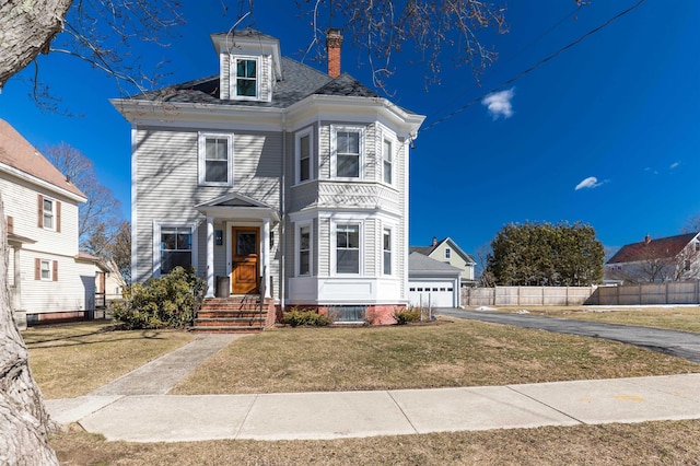 view of front of house with a garage, fence, driveway, a chimney, and a front yard