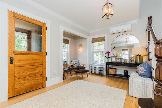 sitting room featuring crown molding, a notable chandelier, radiator heating unit, wood finished floors, and a wall mounted air conditioner