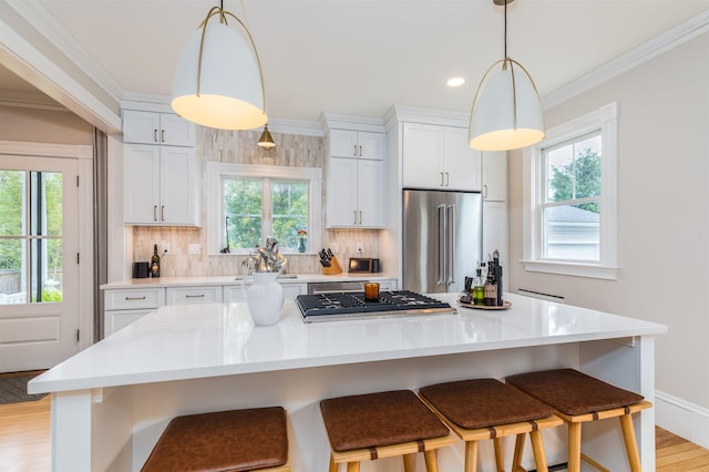 kitchen featuring stainless steel appliances, ornamental molding, backsplash, and light countertops