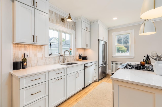 kitchen with stainless steel appliances, decorative backsplash, white cabinetry, a sink, and light wood-type flooring