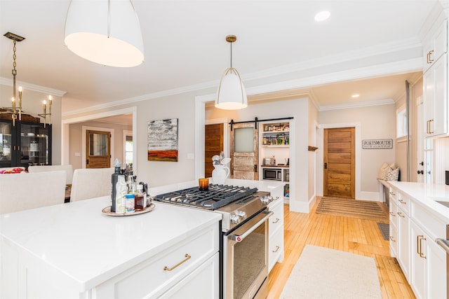 kitchen featuring a center island, light wood finished floors, stainless steel stove, a barn door, and ornamental molding