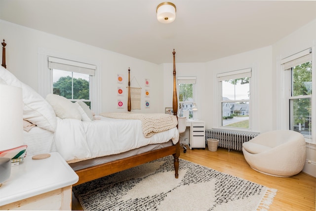 bedroom with multiple windows, wood finished floors, and radiator