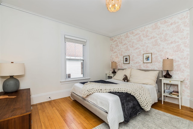 bedroom with wallpapered walls, wood-type flooring, baseboards, and ornamental molding