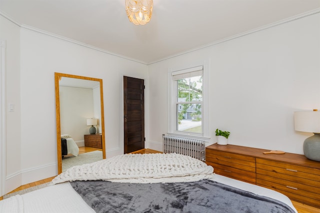 bedroom with baseboards, ornamental molding, wood finished floors, and radiator