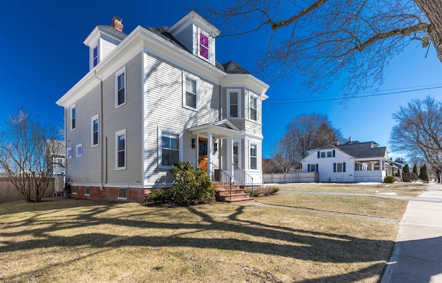 view of front of property with a front lawn, a chimney, and fence