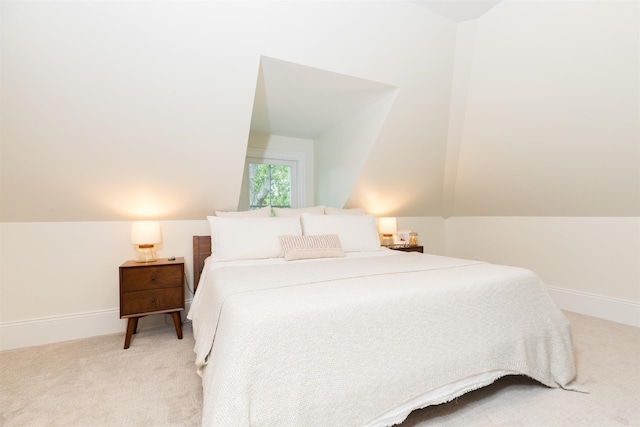 bedroom featuring light colored carpet, vaulted ceiling, and baseboards