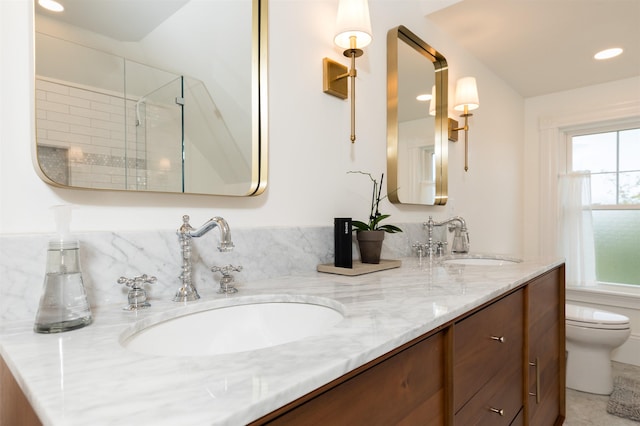 bathroom featuring a sink, a shower stall, toilet, and double vanity