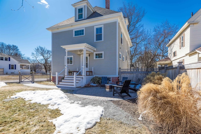 american foursquare style home with a fire pit, a patio area, a chimney, and fence