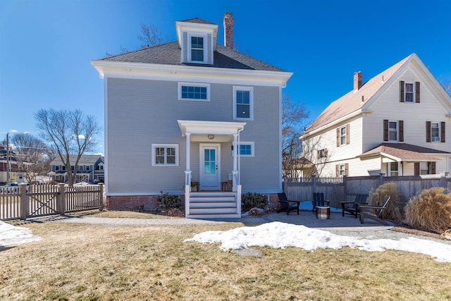 exterior space with a gate, fence, a fire pit, and a lawn