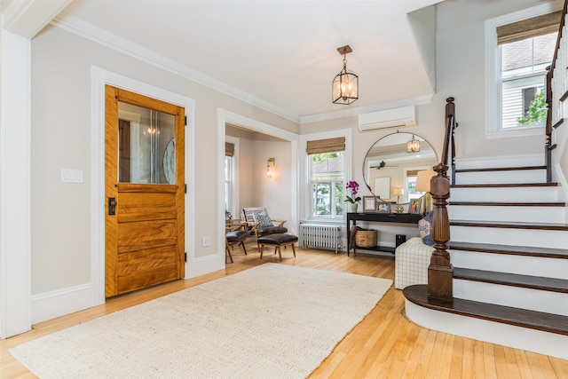 foyer with radiator, a wall unit AC, stairway, and wood finished floors