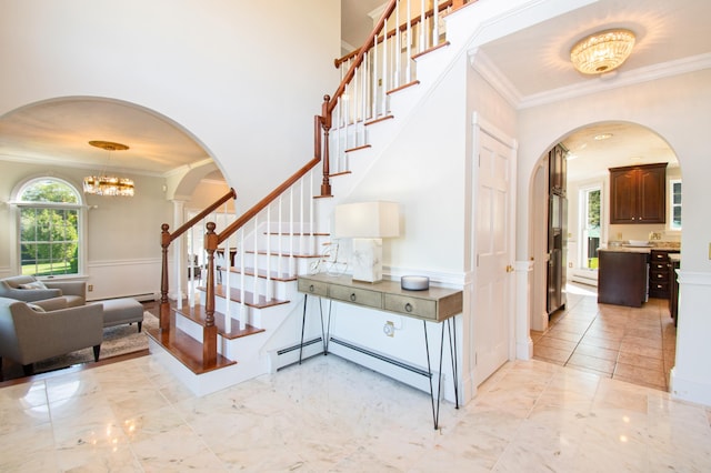 stairs featuring ornamental molding, arched walkways, and marble finish floor