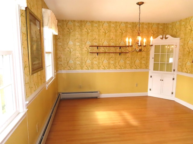 unfurnished dining area with a wainscoted wall, baseboard heating, wood finished floors, and wallpapered walls